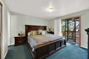 Bedroom featuring baseboards, dark carpet, and access to exterior