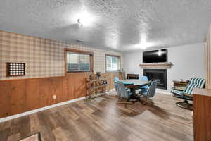 Dining area with wood finished floors, a textured ceiling, a fireplace, baseboards, and visible vents