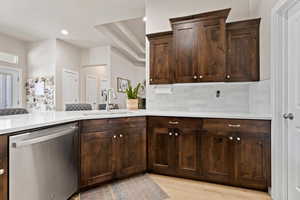 Kitchen featuring dishwasher, tasteful backsplash, a sink, and light countertops