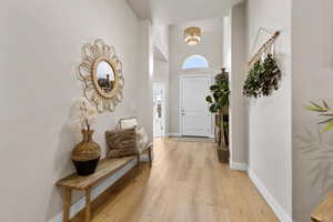 Foyer entrance featuring baseboards, light wood-style flooring, and a high ceiling