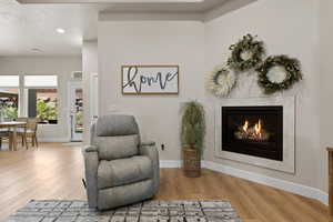 Living area with recessed lighting, wood finished floors, a tile fireplace, and baseboards