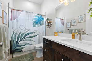 Full bath with a shower with curtain, wood finished floors, vanity, and toilet