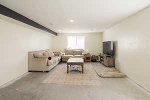 Living room featuring unfinished concrete floors and recessed lighting
