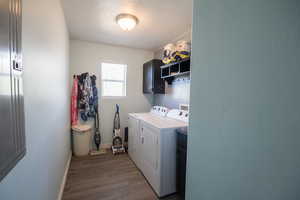 Clothes washing area with a textured ceiling, baseboards, independent washer and dryer, cabinet space, and dark wood-type flooring