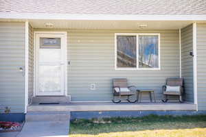 View of exterior entry featuring roof with shingles