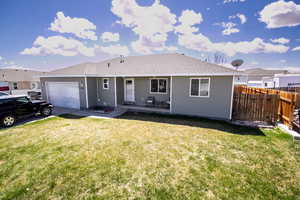 Ranch-style house featuring an attached garage, fence, roof with shingles, and a front lawn