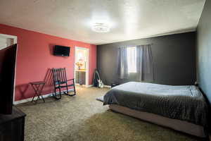 Carpeted bedroom with baseboards, a textured ceiling, and ensuite bathroom