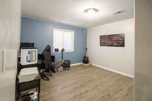 Home office featuring baseboards, wood finished floors, and visible vents