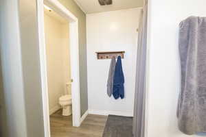 Full bath featuring wood finished floors, toilet, and baseboards