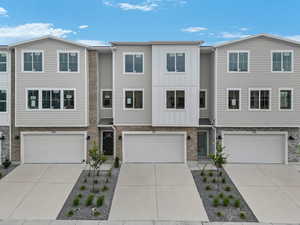 Townhome / multi-family property featuring board and batten siding, driveway, and a garage