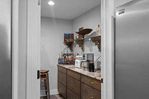 Bar with wood finished floors and stainless steel refrigerator