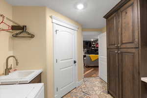 Clothes washing area with washer / dryer, cabinet space, a sink, and recessed lighting