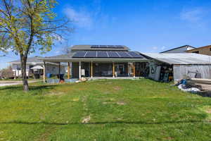 View of front of property featuring a patio, a front yard, and solar panels