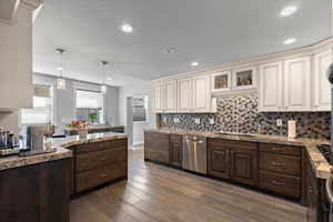 Kitchen with dishwasher, tasteful backsplash, dark brown cabinets, and a sink