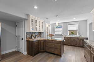 Kitchen featuring dark brown cabinets, a peninsula, and dark wood-style flooring