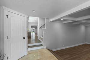 Interior space with baseboards, beam ceiling, a textured ceiling, and recessed lighting