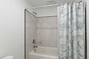 Bathroom featuring toilet and shower / tub combo with curtain