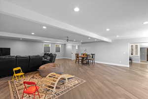 Living room with light wood-type flooring, baseboards, recessed lighting, and beamed ceiling