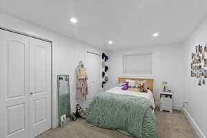 Carpeted bedroom with multiple closets, baseboards, and recessed lighting