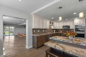 Kitchen featuring stainless steel appliances, a sink, dark wood-style flooring, decorative backsplash, and pendant lighting