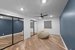 Bedroom featuring a textured ceiling, baseboards, a ceiling fan, wood finished floors, and multiple closets