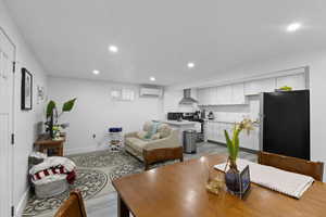 Living area featuring baseboards, a wall mounted AC, and recessed lighting