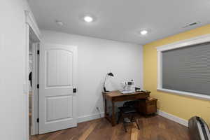 Office space with baseboards, wood finished floors, and visible vents