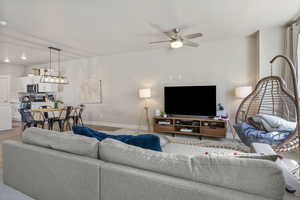 Living area featuring baseboards, light wood-style floors, and ceiling fan