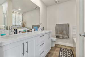 Bathroom featuring baseboards, wood finished floors, a sink, and visible vents