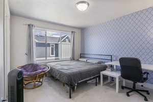 Bedroom featuring wallpapered walls, carpet floors, and an accent wall