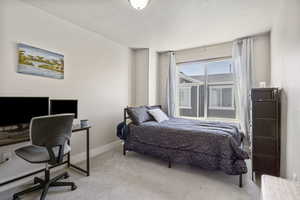 Bedroom featuring light colored carpet, baseboards, and a textured ceiling