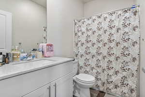 Bathroom featuring a shower with curtain, vanity, and toilet