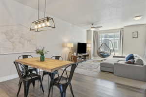 Dining space with baseboards, wood finished floors, a textured ceiling, and ceiling fan