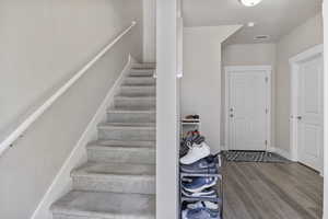 Stairway with baseboards, wood finished floors, and visible vents