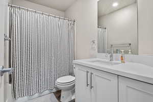 Bathroom with toilet, vanity, shower / tub combo with curtain, and recessed lighting