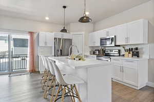 Kitchen with a sink, a breakfast bar, stainless steel appliances, light wood finished floors, and backsplash