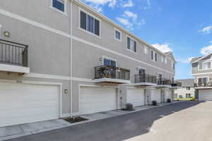 Back of house featuring cooling unit, a residential view, a garage, and stucco siding