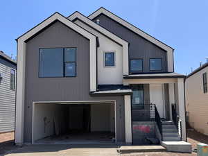 View of front of home featuring an attached garage, concrete driveway, and covered porch