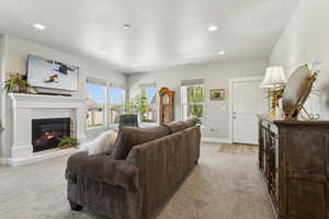 Living room with light colored carpet, gas insert fireplace, and recessed lighting