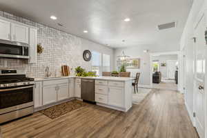 Kitchen with a peninsula/island stainless steel appliances, and light quartz countertops