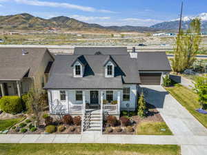 View of front of house featuring concrete driveway, a mountain view, roof with shingles, and covered porch