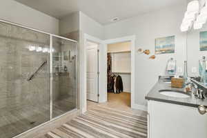 Full bath featuring a sink, a stall shower, a walk in closet, double vanity