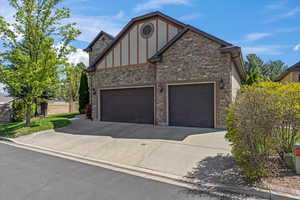 View of front of house featuring concrete driveway, brick siding, stone siding, and a garage