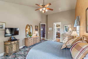Bedroom with high vaulted ceiling, ensuite bathroom, ceiling fan, baseboards, and visible vents