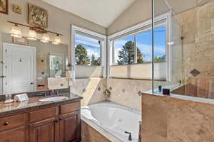 Bathroom featuring lofted ceiling, a jetted tub, vanity, and a walk in shower