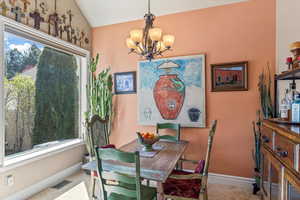 Dining area featuring lofted ceiling, baseboards, visible vents, and an inviting chandelier