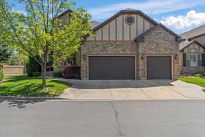 English style home with an attached garage, a front lawn, brick siding, and concrete driveway