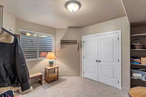 Sitting room featuring a textured ceiling, carpet flooring, and baseboards
