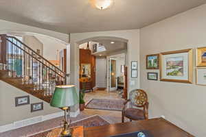 Foyer with arched walkways, stairway, visible vents, and baseboards