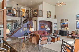 Carpeted living room with arched walkways, recessed lighting, a high ceiling, stairs, and ceiling fan
